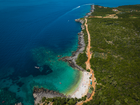 Aerial view of Aquarium Beach with turquoise waters rocky cliffs and lush green hills in Jala Vlore County Albania. Aerial view of Aquarium Beach with turquoise waters rocky cliffs and lush green hills in Jala Vlore County Albania.