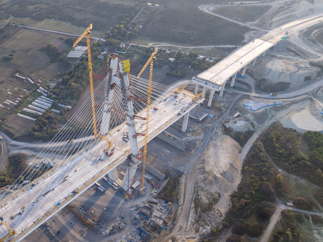 Aerial view of a cable stayed bridge under construction with tall yellow cranes concrete pillars and steel cables spanning across a rural landscape in Istanbul Istanbul Turkiye.