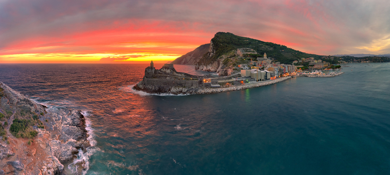 Aerial view of Chiesa di San Pietro on the rocky promontory at sunset with the colorful coastal town and calm sea in Portovenere Liguria Italy. Aerial view of Chiesa di San Pietro on the rocky promontory at sunset with the colorful coastal town and calm sea in Portovenere Liguria Italy.