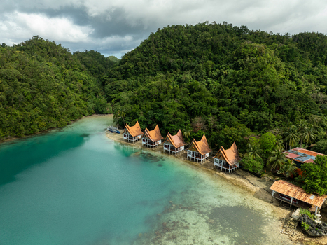 Aerial view of Bucas Grande featuring a row of stilt bungalows nestled along a turquoise lagoon surrounded by lush tropical hills in Siargao Philippines. Aerial view of Bucas Grande featuring a row of stilt bungalows nestled along a turquoise lagoon surrounded by lush tropical hills in Siargao Philippines.