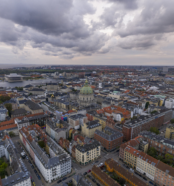 Aerial view of Frederik s Church with its iconic green dome surrounded by historic urban rooftops and streets under a cloudy sky Copenhagen Denmark. Aerial view of Frederik s Church with its iconic green dome surrounded by historic urban rooftops and streets under a cloudy sky Copenhagen Denmark.