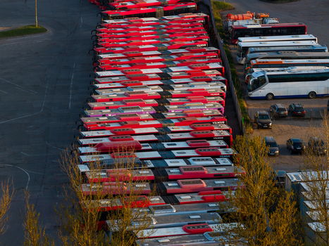 Vilnius County Lithuania 01 May 2026 Aerial view of a large fleet of red public transport buses parked in neat rows at a bus depot during the golden hour. Vilnius County Lithuania 01 May 2026 Aerial view of a large fleet of red public transport buses parked in neat rows at a bus depot during the golden hour.