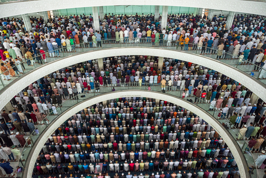 Dhaka Bangladesh 19 June 2026 Aerial view of a large crowd of men praying inside a multi level mosque in Dhaka Bangladesh with rows of worshippers standing on circular balconies.