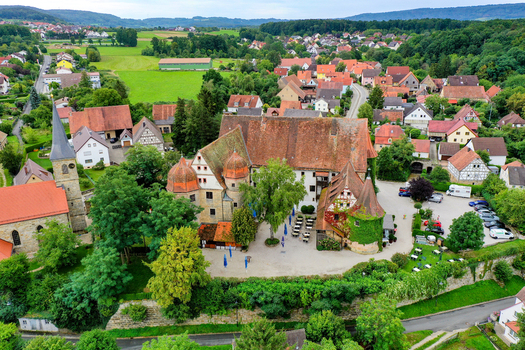 Wiesenthau Germany 09 May 2026 Aerial view of Schloss Wiesenthau with its historic stone walls red tiled roofs and lush courtyard surrounded by the village houses and green landscape. Wiesenthau Germany 09 May 2026 Aerial view of Schloss Wiesenthau with its historic stone walls red tiled roofs and lush courtyard surrounded by the village houses and green landscape.