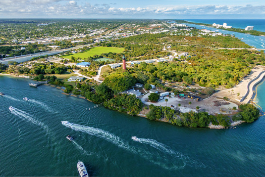 Aerial view of the Jupiter Inlet Lighthouse standing tall against a backdrop of lush greenery where the Loxahatchee River meets the sea Jupiter Florida United States.