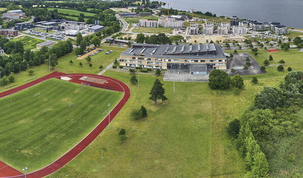 Schleswig Germany 01 July 2026 Aerial view of the Danish Gymnasium and sport park on the former Bundeswehr base Auf Der Freiheit featuring a running track and modern buildings.