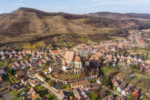 Aerial view of the historic Biertan Fortified Church surrounded by traditional village houses and terraced hills in Biertan Sibiu Romania.