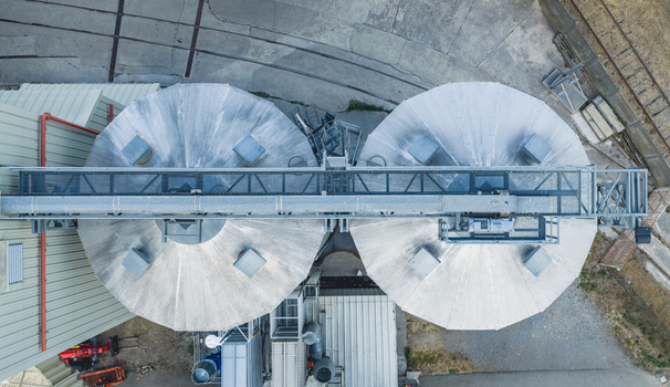 Aerial view of circular grain silos connected by an overhead conveyor bridge at an agricultural storage facility in Le Pouzin Auvergne Rhone Alpes France.