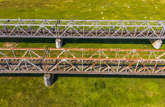 Aerial view of the historic Tczew railway bridges featuring a modern steel truss bridge alongside an older weathered structure over green landscape in Tczew Pomeranian Voivodeship Poland. Aerial view of the historic Tczew railway bridges featuring a modern steel truss bridge alongside an older weathered structure over green landscape in Tczew Pomeranian Voivodeship Poland.
