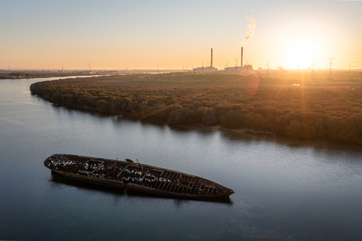 Aerial view of the rusted Santiago shipwreck resting in the calm waters near mangroves with a power station in the background at sunset near Port Adelaide South Australia Australia.