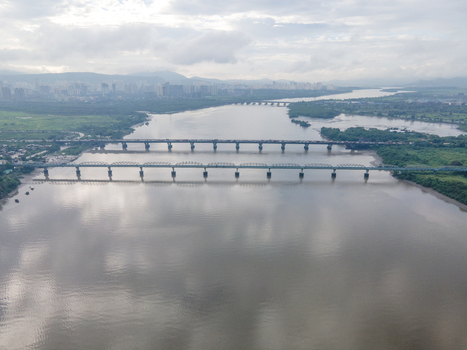 Aerial view of the Thane Creek bridges spanning the wide river with lush green banks and the distant city skyline under a cloudy sky in Thane Maharashtra India. Aerial view of the Thane Creek bridges spanning the wide river with lush green banks and the distant city skyline under a cloudy sky in Thane Maharashtra India.