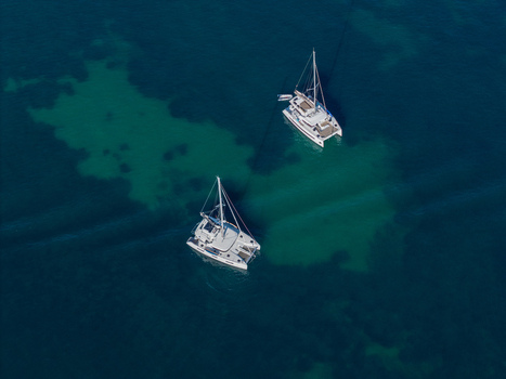 Aerial view of two catamarans anchored in the clear turquoise waters off the coast of Antibes Provence Alpes Cote d Azur France. Aerial view of two catamarans anchored in the clear turquoise waters off the coast of Antibes Provence Alpes Cote d Azur France.