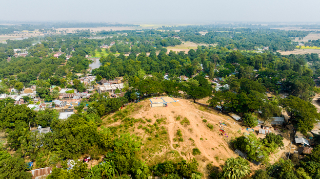Aerial view of the historic mound at Rohanpur surrounded by lush green trees rural village houses and agricultural fields in Rohanpur Rajshahi Division Bangladesh.