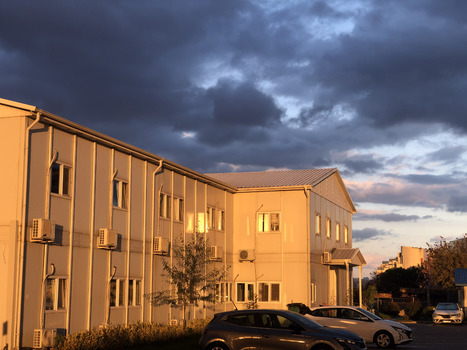 View of a modern office building with golden sunset light reflecting on the facade under a dramatic cloudy sky in Avcilar Istanbul Turkiye. View of a modern office building with golden sunset light reflecting on the facade under a dramatic cloudy sky in Avcilar Istanbul Turkiye.