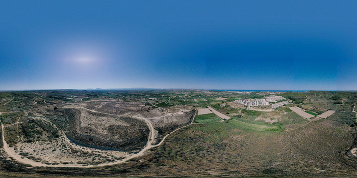 Aerial view of the Yacimiento Arqueologico Cabezo Pequeno del Estano archaeological site and surrounding arid landscape under a clear blue sky Alicante Comunidad Valenciana Spain.