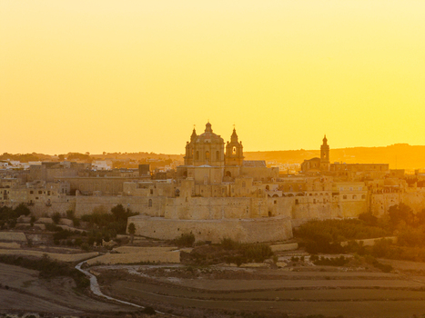 Aerial view of the historic fortified city of Mdina with its cathedral dome and stone walls illuminated by the warm golden light of sunset in Mdina Malta. Aerial view of the historic fortified city of Mdina with its cathedral dome and stone walls illuminated by the warm golden light of sunset in Mdina Malta.