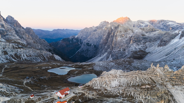 Aerial view of Tre Cime di Lavaredo with the Locatelli mountain hut and alpine lakes surrounded by rugged peaks at sunrise Auronzo di Cadore Veneto Italy. Aerial view of Tre Cime di Lavaredo with the Locatelli mountain hut and alpine lakes surrounded by rugged peaks at sunrise Auronzo di Cadore Veneto Italy.