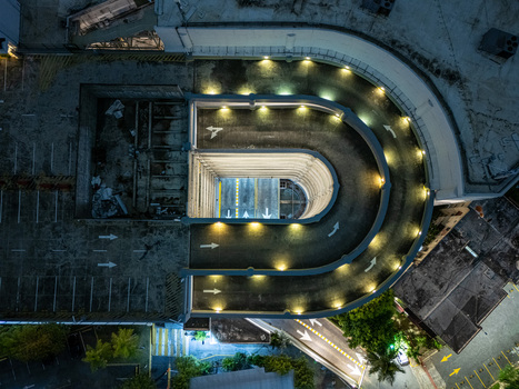 Aerial view of an illuminated U shaped parking garage ramp at night with road markings and surrounding urban infrastructure in Santo Domingo Distrito Nacional Dominican Republic. Aerial view of an illuminated U shaped parking garage ramp at night with road markings and surrounding urban infrastructure in Santo Domingo Distrito Nacional Dominican Republic.