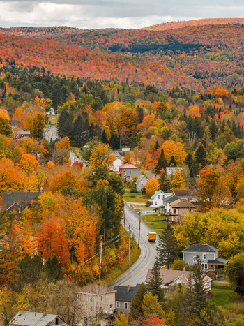 Aerial view of the village of Island Pond s fall foliage with vibrant autumn trees a winding road and houses in Brighton Vermont USA. Aerial view of the village of Island Pond s fall foliage with vibrant autumn trees a winding road and houses in Brighton Vermont USA.