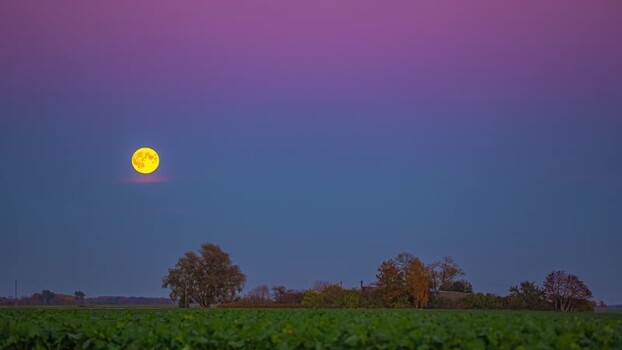 View of full moon over a rural field in Latvia.