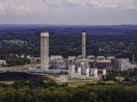 Aerial view of the Gallatin Fossil Plant a coal fired power station featuring tall smokestacks and industrial infrastructure surrounded by lush green forests in Gallatin TN United States.
