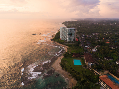 Aerial view of Gintota beach featuring a luxury coastal resort swimming pool and lush tropical greenery during sunset in Galle Southern Province Sri Lanka. Aerial view of Gintota beach featuring a luxury coastal resort swimming pool and lush tropical greenery during sunset in Galle Southern Province Sri Lanka.