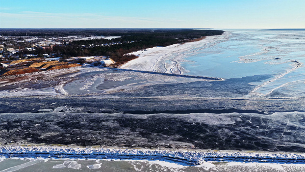 Aerial view of a frozen coastline with ice covered sea snow covered land and a forest in Latvia. Aerial view of a frozen coastline with ice covered sea snow covered land and a forest in Latvia.