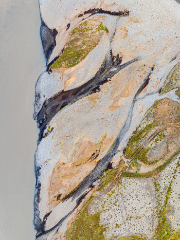 Aerial view of a braided river system with intricate water channels sediment deposits and patches of green vegetation in Iceland. Aerial view of a braided river system with intricate water channels sediment deposits and patches of green vegetation in Iceland.