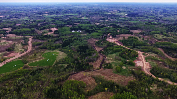 Aerial view of wind turbine maintenance roads and access paths winding through a vast landscape of green forests meadows and cleared construction areas in Latvija. Aerial view of wind turbine maintenance roads and access paths winding through a vast landscape of green forests meadows and cleared construction areas in Latvija.