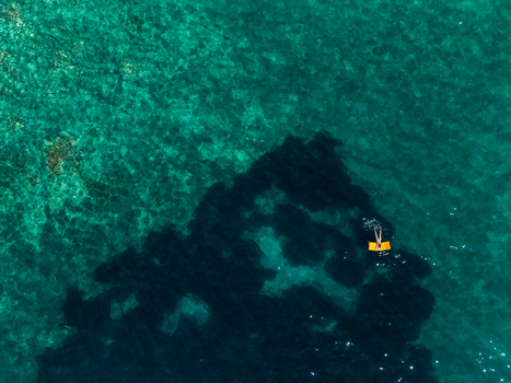 Aerial view of a person relaxing on a yellow inflatable mattress in the crystal clear turquoise waters of Aquarium Beach Jala Vlore County Albania. Aerial view of a person relaxing on a yellow inflatable mattress in the crystal clear turquoise waters of Aquarium Beach Jala Vlore County Albania.