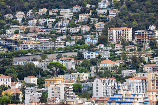 Aerial view of the hillside residential area featuring dense Mediterranean architecture terraced buildings lush green trees and winding streets in Nice Provence Alpes Cote d Azur France. Aerial view of the hillside residential area featuring dense Mediterranean architecture terraced buildings lush green trees and winding streets in Nice Provence Alpes Cote d Azur France.