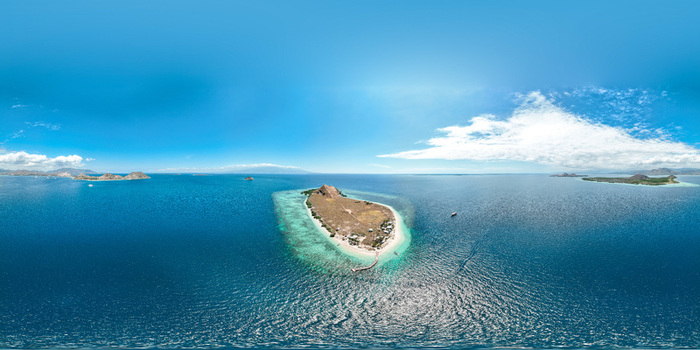 Aerial view of Pulau Kenawa surrounded by turquoise coral reefs and deep blue sea under a clear sky in Poto Tano West Nusa Tenggara Indonesia. Aerial view of Pulau Kenawa surrounded by turquoise coral reefs and deep blue sea under a clear sky in Poto Tano West Nusa Tenggara Indonesia.