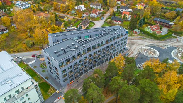 Aerial view of a modern grey apartment building surrounded by autumn trees and suburban houses in Sweden. Aerial view of a modern grey apartment building surrounded by autumn trees and suburban houses in Sweden.