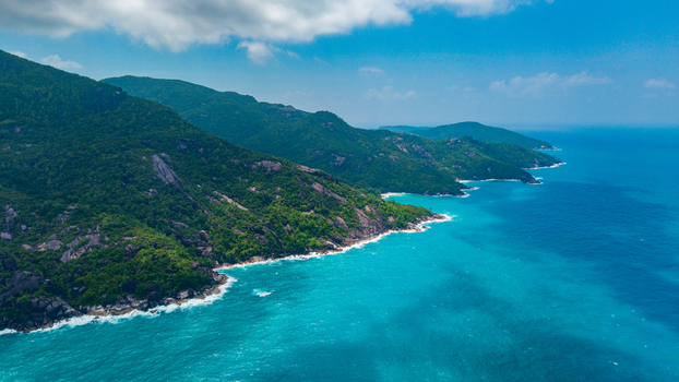 Aerial view of the lush green coastline near Anse Soleil Beachcomber Hotel featuring turquoise waters rocky cliffs and dense tropical vegetation in Mahe Baie Lazare Seychelles.
