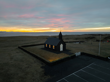 Aerial view of the iconic black wooden church of Budir surrounded by a stone wall in the coastal landscape at sunset in Budir Snaefellsbaer Iceland. Aerial view of the iconic black wooden church of Budir surrounded by a stone wall in the coastal landscape at sunset in Budir Snaefellsbaer Iceland.