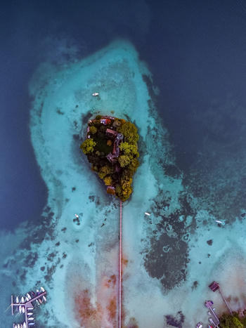 Aerial view of the small island in Attersee with a historic building and wooden pier surrounded by turquoise water and small boats in Vocklabruck District Upper Austria Austria.