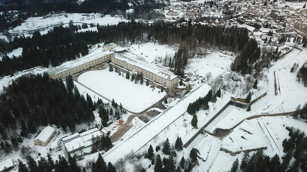 Aerial view of Le Fort des Rousses with its historic stone buildings surrounded by snow covered pine forests and winter landscape in Les Rousses Bourgogne Franche Comte France.
