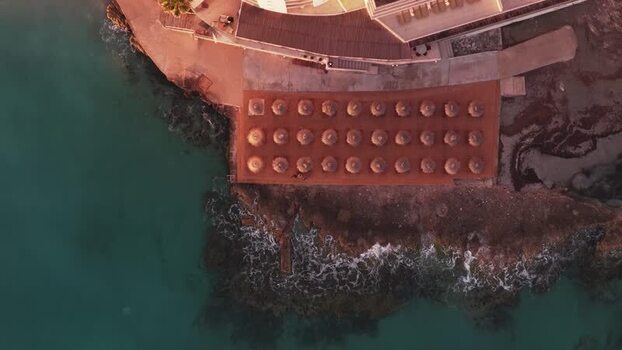Aerial view of straw umbrellas on a coastal terrace Spain.