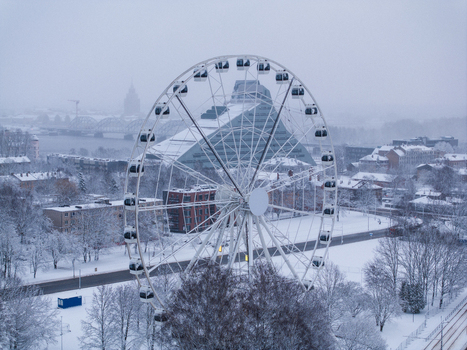 Aerial view of a Ferris wheel standing in a snow covered park with the National Library of Latvia in the background in Riga Latvia. Aerial view of a Ferris wheel standing in a snow covered park with the National Library of Latvia in the background in Riga Latvia.