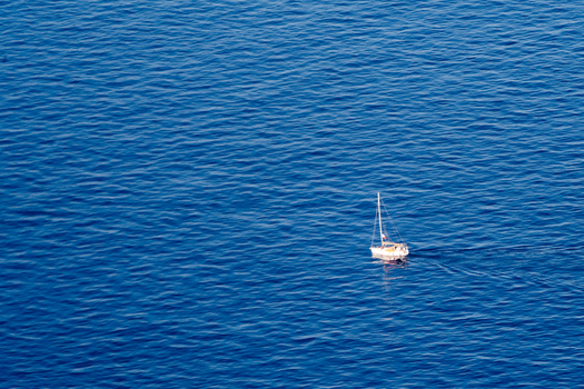 View of a small white sailboat gliding across the deep blue Mediterranean Sea near the coast of Nice Provence Alpes Cote d Azur France. View of a small white sailboat gliding across the deep blue Mediterranean Sea near the coast of Nice Provence Alpes Cote d Azur France.