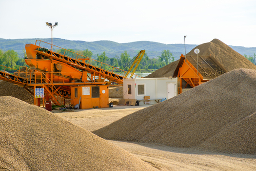 View of industrial machinery and large gravel piles at a construction or mining site under a clear sky in Novi Sad Vojvodina Serbia. View of industrial machinery and large gravel piles at a construction or mining site under a clear sky in Novi Sad Vojvodina Serbia.