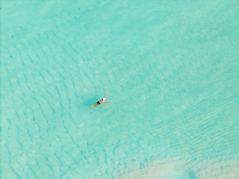 Aerial view of a swimmer in the turquoise waters a serene escape in the pristine seascape of Kan island Dhidhdhoo Thiladhunmathi Atoll Maldives.