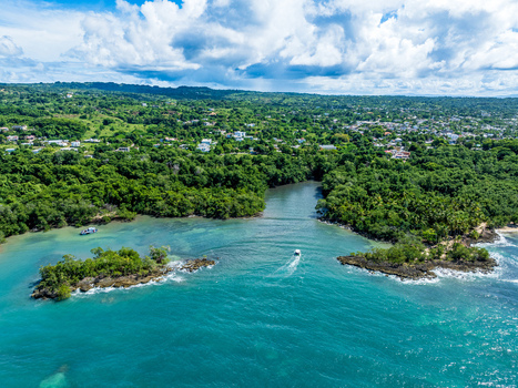 Aerial view of Rio San Juan with a small boat navigating the turquoise waters near lush green islets and coastal vegetation in Rio San Juan Maria Trinidad Sanchez Dominican Republic. Aerial view of Rio San Juan with a small boat navigating the turquoise waters near lush green islets and coastal vegetation in Rio San Juan Maria Trinidad Sanchez Dominican Republic.