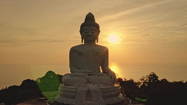 Aerial view of the Big Buddha statue illuminated by the warm golden light of the setting sun over the ocean in Phuket Phuket Thailand. Aerial view of the Big Buddha statue illuminated by the warm golden light of the setting sun over the ocean in Phuket Phuket Thailand.