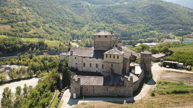 Aerial view of Sarriod de la Tour Castle with its medieval stone walls and central tower surrounded by lush green hills and vineyards in Aosta Valley Italy. Aerial view of Sarriod de la Tour Castle with its medieval stone walls and central tower surrounded by lush green hills and vineyards in Aosta Valley Italy.