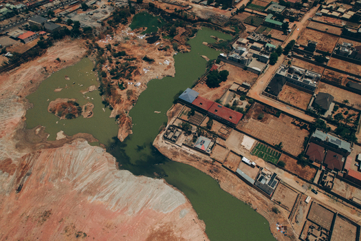 Aerial view of a green water pond surrounded by arid landscape and residential buildings near Kano Madobi Kiru Road in Watari Kano Nigeria. Aerial view of a green water pond surrounded by arid landscape and residential buildings near Kano Madobi Kiru Road in Watari Kano Nigeria.