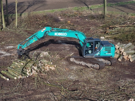 Nederland 06 July 2026 Aerial view of a Kobelco excavator working in a field with piles of cut logs and branches. Nederland 06 July 2026 Aerial view of a Kobelco excavator working in a field with piles of cut logs and branches.