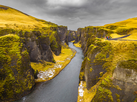 Aerial view of the serpentine river carves through the verdant canyon its steep walls adorned with moss under a sky heavy with clouds Fjaðrárgljúfur Skaftárhreppur Iceland. Aerial view of the serpentine river carves through the verdant canyon its steep walls adorned with moss under a sky heavy with clouds Fjaðrárgljúfur Skaftárhreppur Iceland.
