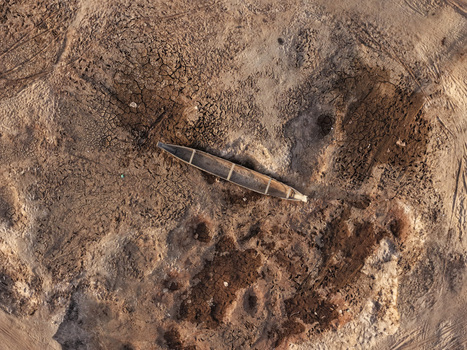 Aerial view of a traditional wooden boat stranded on the dry cracked earth of the Jadukata River bed in Sunamganj Sylhet Division Bangladesh. Aerial view of a traditional wooden boat stranded on the dry cracked earth of the Jadukata River bed in Sunamganj Sylhet Division Bangladesh.