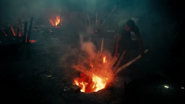 View of a worker tending to a fire in a workshop Bangladesh. View of a worker tending to a fire in a workshop Bangladesh.